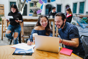 Happy young mexican college students working together on laptop in latin america