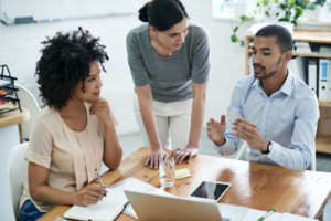 Stock image of meeting at a table with three team members.