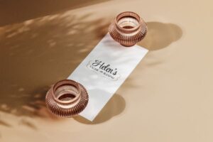 "Helen's Facial & Waxing" is written in cursive font on a white paper, set against a tan background with two bronze vases at each end of the paper.