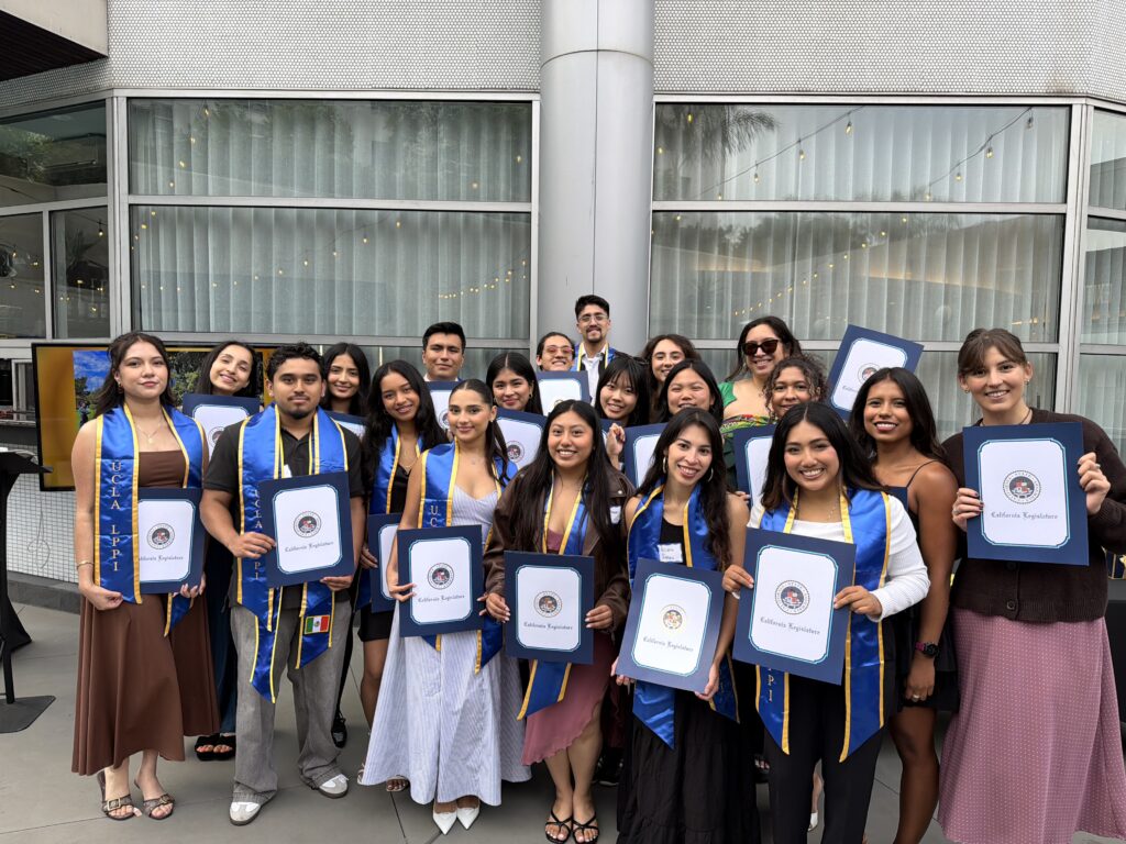Students working with LPPI smile with Scrolls of Recognition from the California State Assembly. Many are wearing blue graduation stoles.